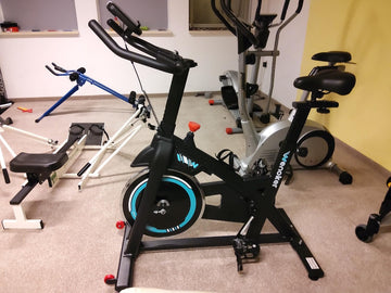 Ein gut organisiertes Homegym in einer kleinen Wohnung mit Wenoker Heimtrainer und ordentlich verstautem Fitnessequipment – ein Beispiel für effiziente Raumnutzung.