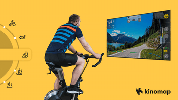 A tablet mounted on a Wenoker JC318 exercise bike displaying the Kinomap virtual cycling interface during an active home workout session
