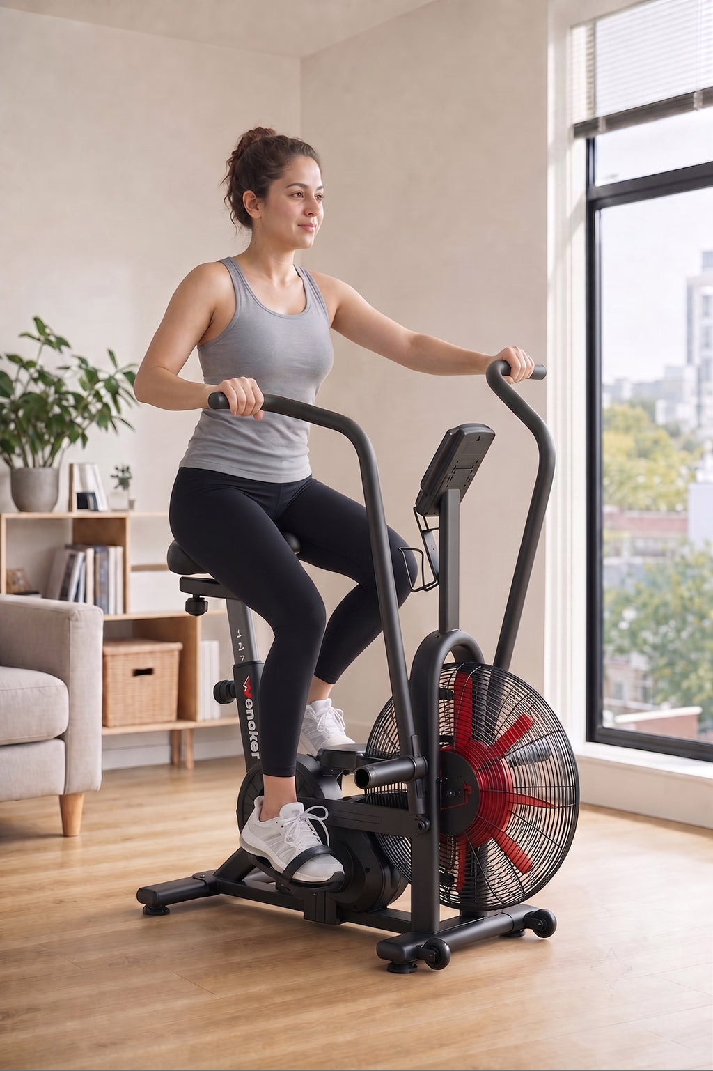 Woman riding a Wenoker K29650 dual-action air bike beside a bright apartment window
